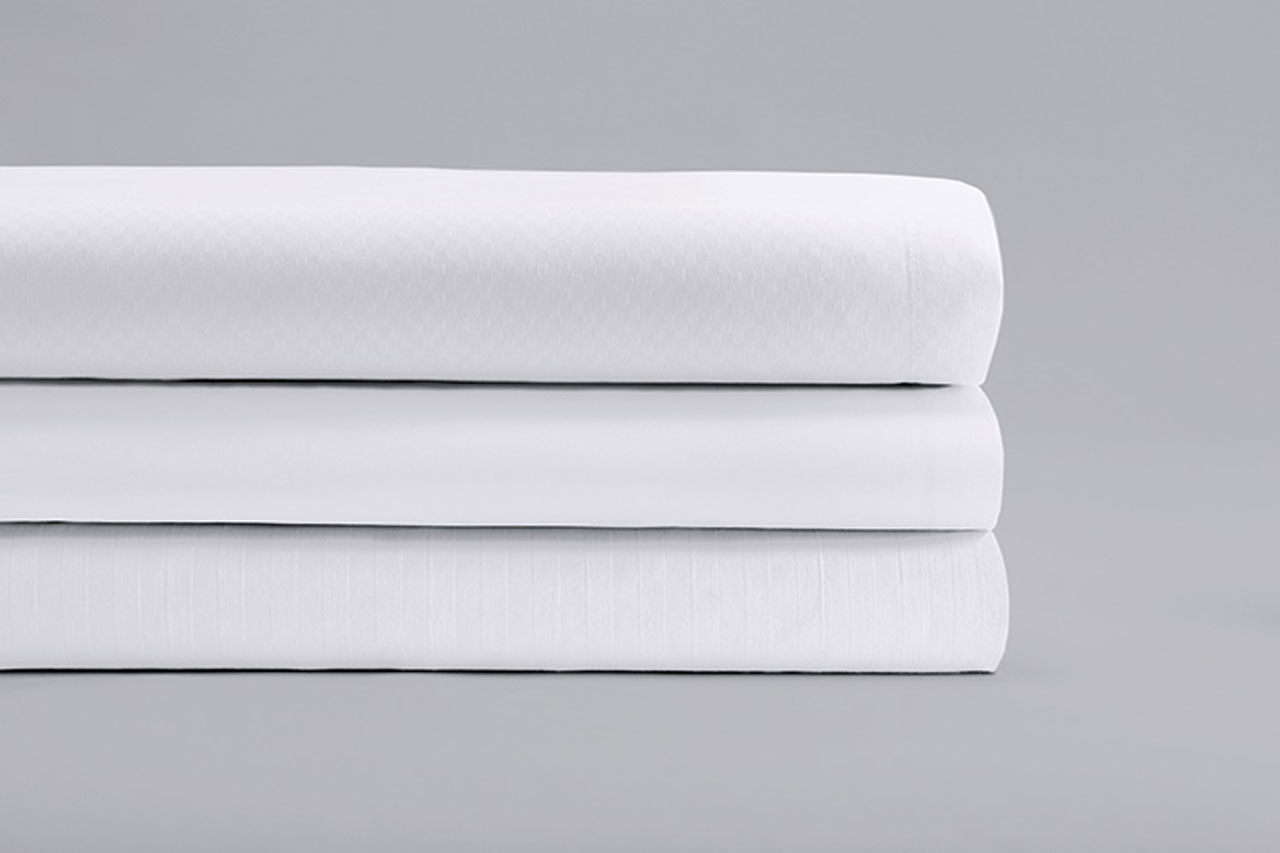 How does the construction of Standard Textile's ComforTwill white sheets withstand industrial laundering?